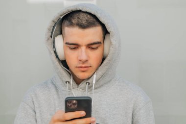 Dışarıda cep telefonu ve kulaklığı olan bir genç.