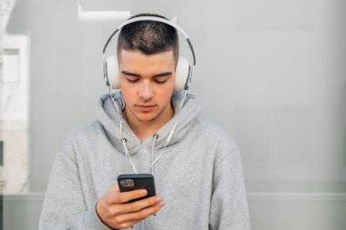Kulaklık ve cep telefonu olan genç bir adam.