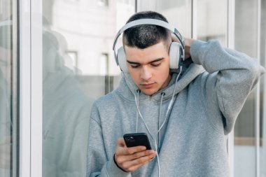 Kulaklıklı ve cep telefonu olan bir genç.