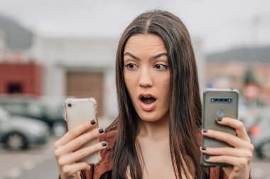 girl looking at mobile phones with an expression of doubt or surprise