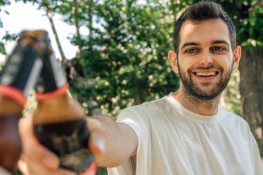 Yazın içki içen genç adam mutlu kadeh kaldırıyor.