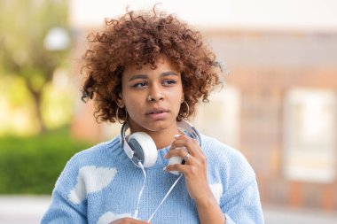 Sokakta kulaklık takan Afro-Amerikan kız.