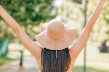 girl from behind with hat enjoying the summer sun outdoors