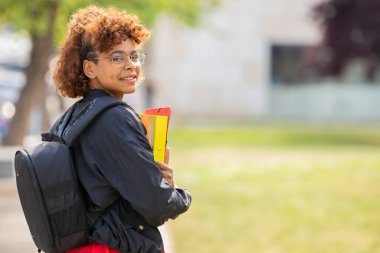 Kampüste kitap ve sırt çantalı Afro-Amerikan öğrenci.