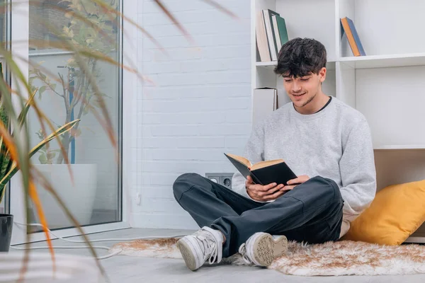 student or young man reading a textbook at home