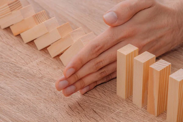 Hand Stops Falling Dominoes Wooden Puzzle — Stockfoto