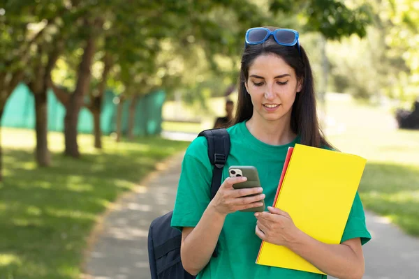 student with books and mobile phone outdoors