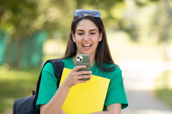 Smiling Student Girl Books Looking Mobile Phone Outdoors — Zdjęcie stockowe