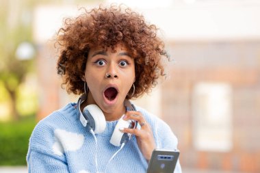 Cep telefonu ve sürpriz ifadesi olan bir kız.