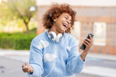 Dışarıda cep telefonuna bakan Afro-Amerikan kadın.