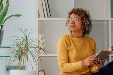 Kız evde rahatça ders kitabı okuyor.