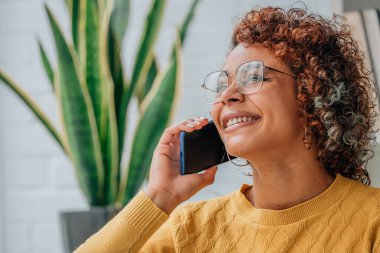 Kadın ya da kız evde cep telefonuyla konuşuyor.