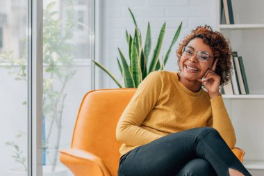 Kız evinde mutlu bir şekilde kanepede oturuyor.