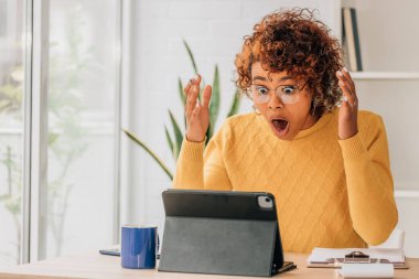 Şaşırmış ifadesi olan bir kadın dizüstü bilgisayara bakıyor.