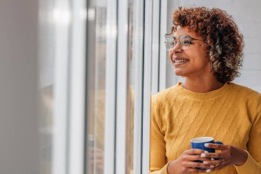 Kız ya da kadın evde rahatça kahve içiyor.