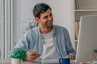 Bilgisayarlı ve cep telefonlu genç adam