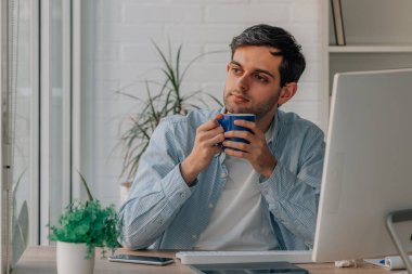 young man with cup of coffee working with computer