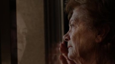 senior woman looking out the window, loneliness