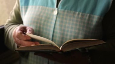 hands of senior woman leafing through and reading the book