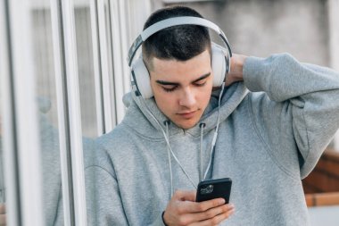 Cep telefonu ve kulaklığı olan genç bir çocuk.