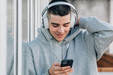 Cep telefonu ve kulaklığı olan genç bir çocuk.