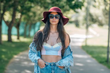 young urban hipster girl strolling outdoors with hat in summer