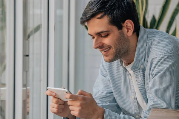 young man chatting or playing games at home or office with mobile phone