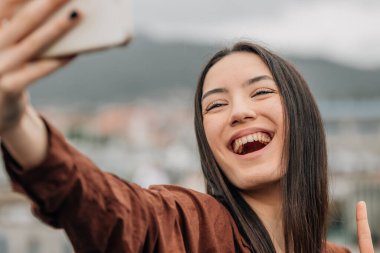 Sokakta cep telefonlu bir kız fotoğraf çekiyor.