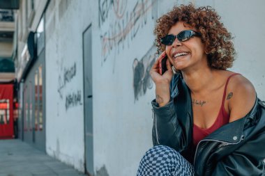 black african american girl talking on mobile phone or smartphone in the street outdoors