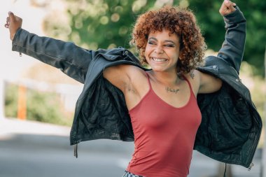 Genç şehirli kız sokaklarda mutlu bir şekilde gülüp dans ediyor.