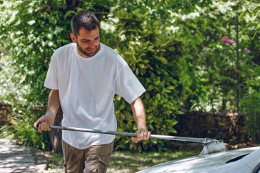 Yazın dışarıda araba yıkayan genç bir adam.