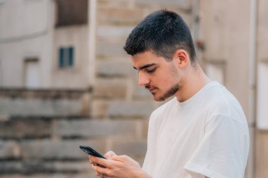 Genç adam cep telefonu ya da akıllı telefonuyla konuşuyor ya da daktilo çekiyor
