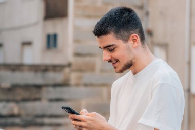 Genç adam cep telefonu ya da akıllı telefonuyla konuşuyor ya da daktilo çekiyor