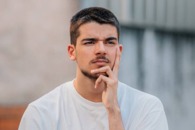 Sokakta yüzünde düşünceli bir ifade olan genç bir adam.