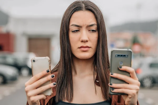 Niezdecydowana Lub Nieufna Dziewczyna Patrząca Telefony Komórkowe Lub Komórkowe — Zdjęcie stockowe