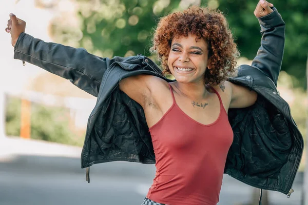 Genç şehirli kız sokaklarda mutlu bir şekilde gülüp dans ediyor.