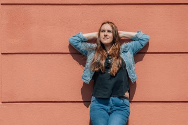 Sokaktaki kadın gevşemiş, duvara yaslanmış.