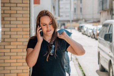 Kadın sokakta cep telefonuyla konuşuyor.