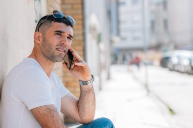 Orta yaşlı bir adam sokakta cep telefonuyla konuşuyor.