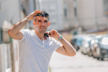 Sokaktaki adam güneş gözlüklü ufka bakıyor.