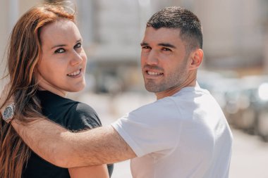 Sokakta yürüyen genç çift kameraya bakıyor.