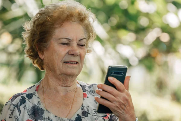 在户外带手机或手机的老年妇女 — 图库照片