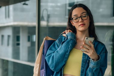young girl with shopping bags and mobile phone