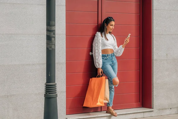 街上的年轻姑娘 提着购物袋和手机 — 图库照片