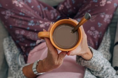 Evde rahatlamış bir kadın kahvesi ve ellerin üst görüntüsü.