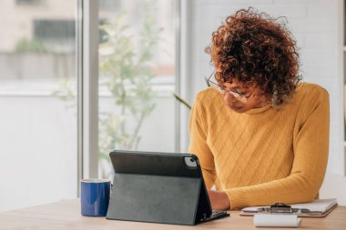 Evde bilgisayarı ya da laptopu olan Afrikalı Amerikalı bir kız var.