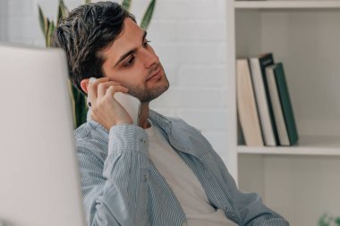 Evde cep telefonuyla konuşan bir adam var.