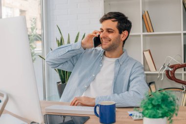 Evde cep telefonuyla konuşan bir adam var.