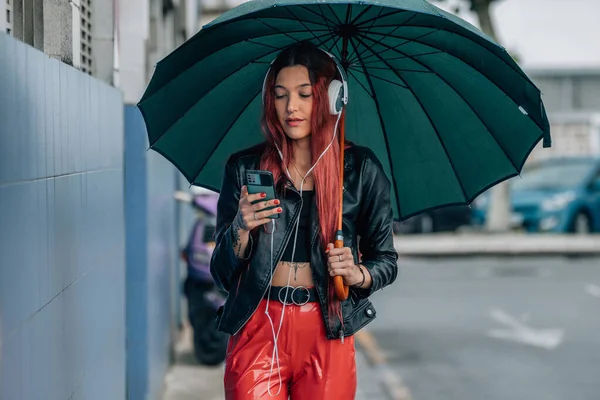 Vörös Hajú Lány Mobiltelefonnal Fülhallgatóval Utcán Esernyővel — Stock Fotó
