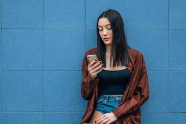 young girl with mobile phone on the street wall